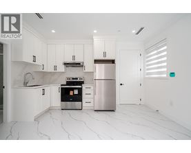 A modern kitchen with white cabinets and marble flooring.