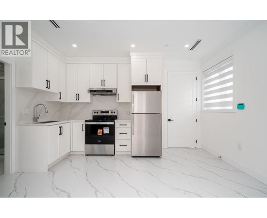 A modern kitchen with white cabinets and marble flooring.