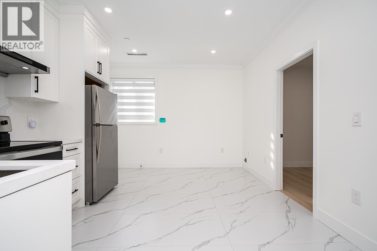 A white kitchen with a marble floor and a refrigerator.