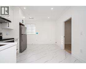 A white kitchen with a marble floor and a refrigerator.