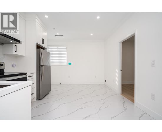 A white kitchen with a marble floor and a refrigerator.