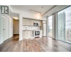 A spacious living room with wooden floors and a large window overlooking a city skyline.