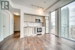 A spacious living room with wooden floors and a large window overlooking a city skyline.