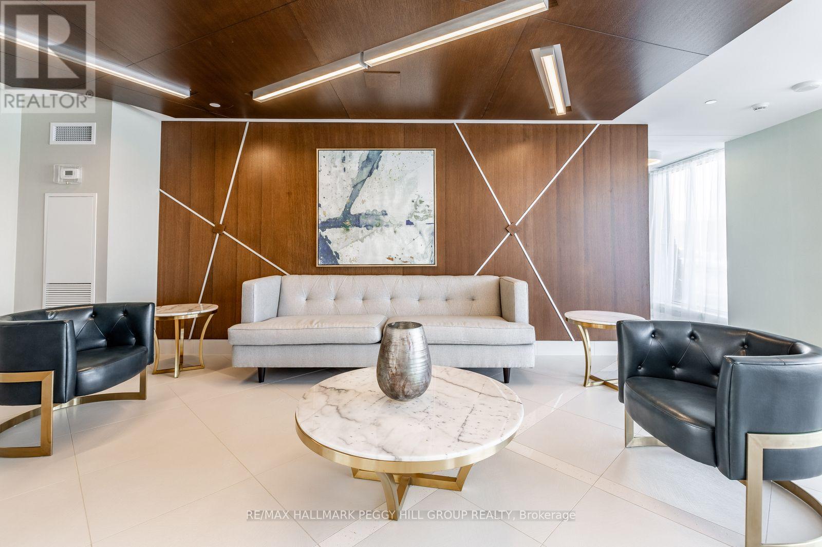 A modern living room with a white sofa, black leather chairs, and a marble coffee table.