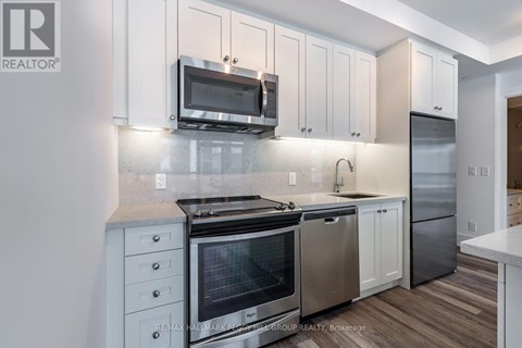 A modern kitchen with white cabinets and stainless steel appliances.