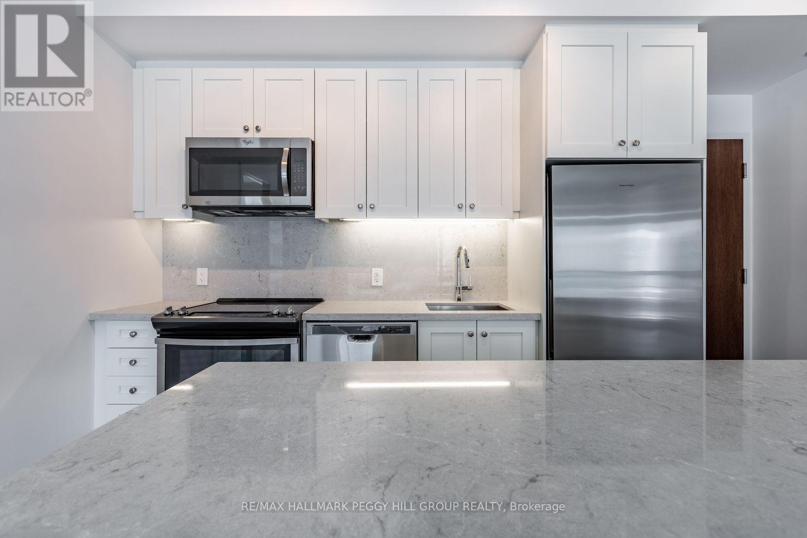 A kitchen with white cabinets and a marble countertop.