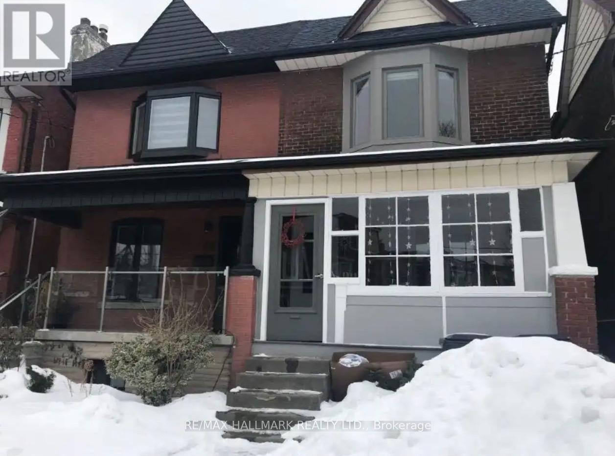 A red brick house with a grey front porch and a snow bank in front.