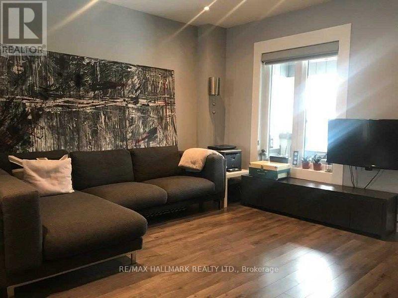 A living room with a grey sofa and a painting on the wall.