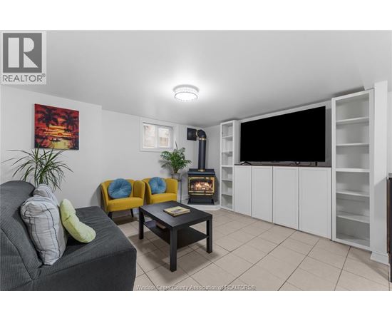 A living room with a grey couch, yellow chairs, a black coffee table, and a flat screen TV.