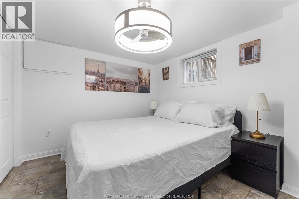 A bedroom with a bed, nightstand, and pictures on the wall.