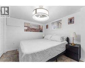 A bedroom with a bed, nightstand, and pictures on the wall.