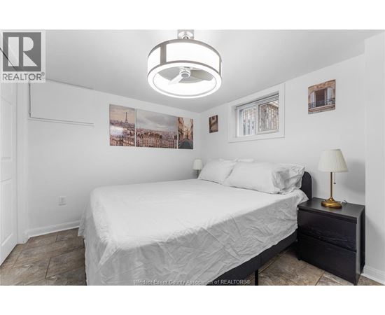 A bedroom with a bed, nightstand, and pictures on the wall.