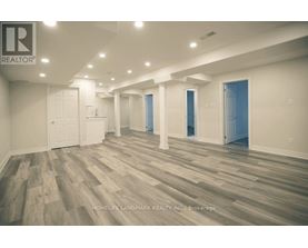 A spacious room with wooden flooring and white walls.