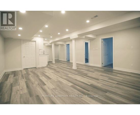 A spacious room with wooden flooring and white walls.