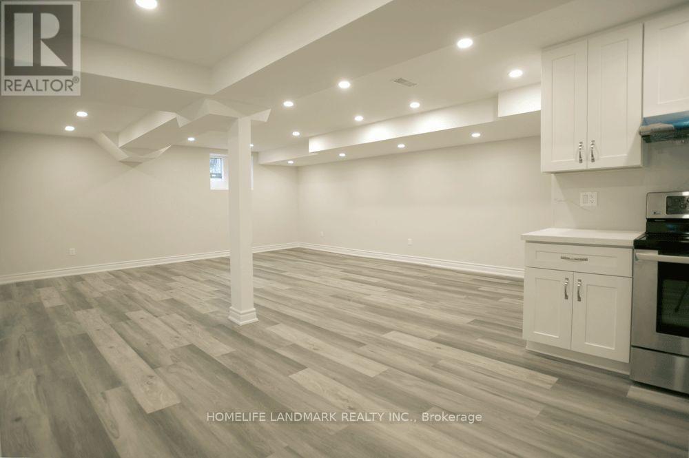 A spacious kitchen with white cabinets and a wooden floor.
