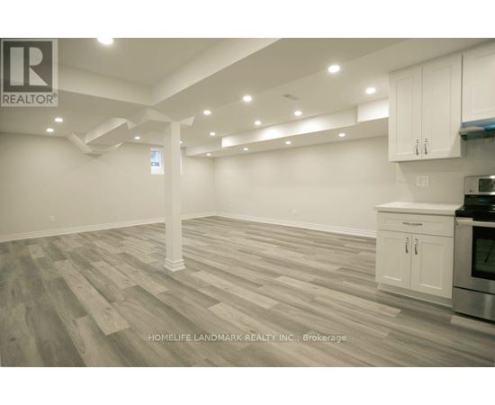 A spacious kitchen with white cabinets and a wooden floor.