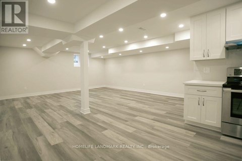 A spacious kitchen with white cabinets and a wooden floor.