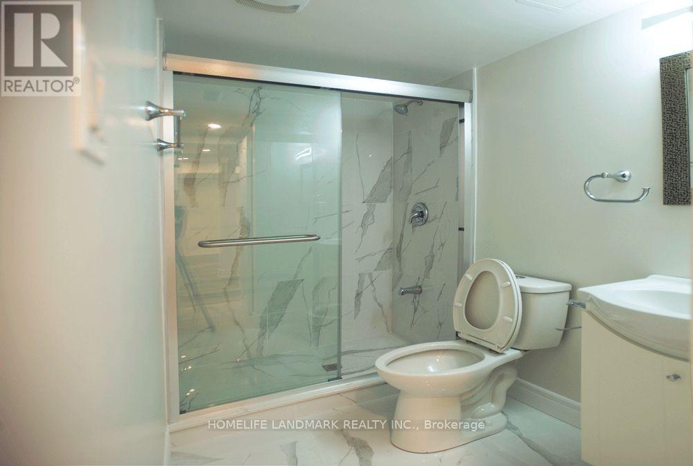 A bathroom with a glass shower door and a toilet.