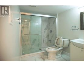 A bathroom with a glass shower door and a toilet.