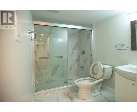A bathroom with a glass shower door and a toilet.