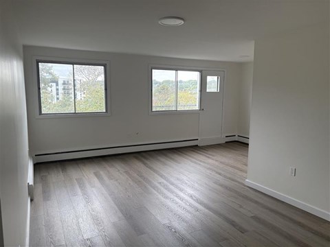 A room with two windows and wooden flooring.