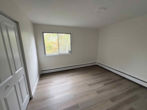 A room with a window and wooden flooring.