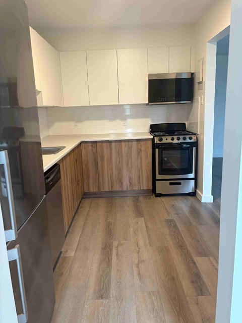 A kitchen with a black stove top oven and wooden floors.