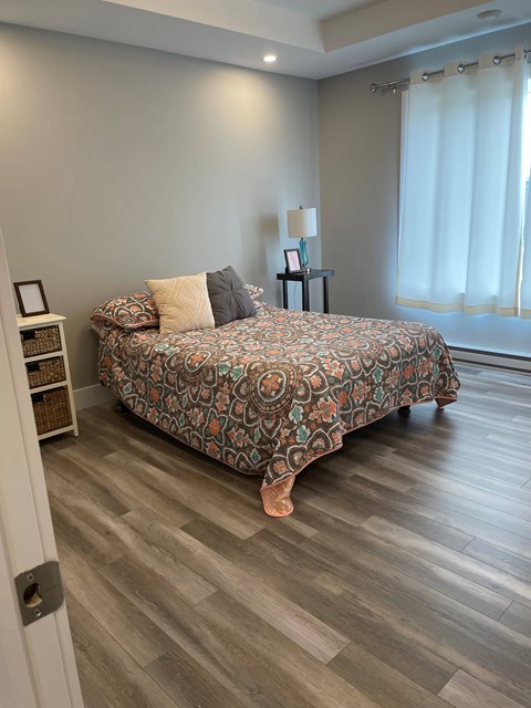 A bedroom with a patterned bedspread and a wooden floor.