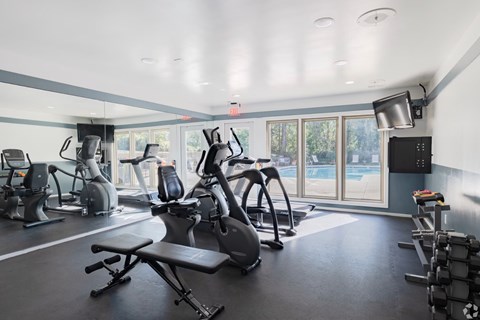 A gym with a variety of exercise equipment including treadmills, stationary bikes, and weight machines.