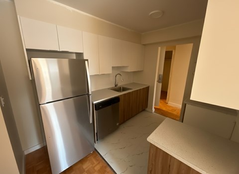 A kitchen with a refrigerator, sink, and countertop.