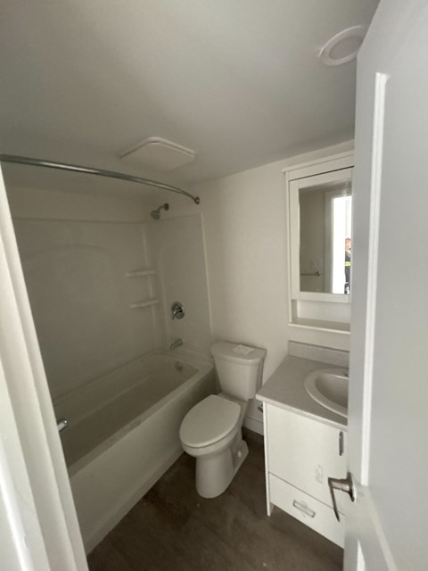 A white bathroom with a toilet, sink, and bathtub.