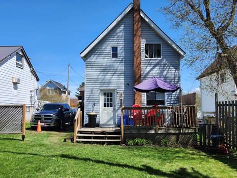 A blue house with a white fence and a tree in front.