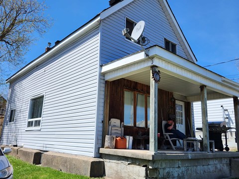 A man is sitting on a chair on a porch.