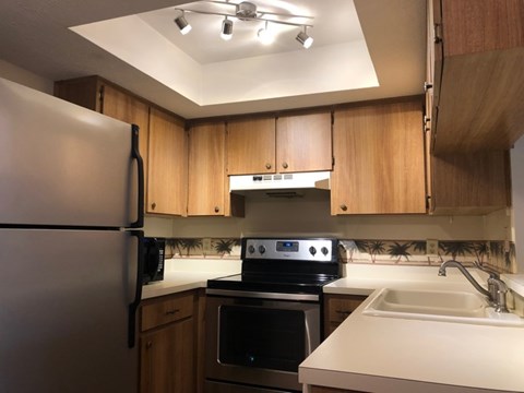 A kitchen with a refrigerator, microwave, oven, and sink.