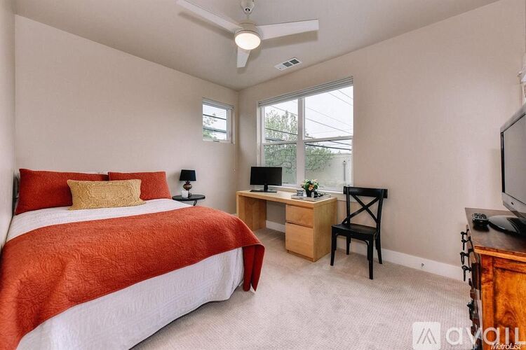 A bedroom with a bed, desk, and television.