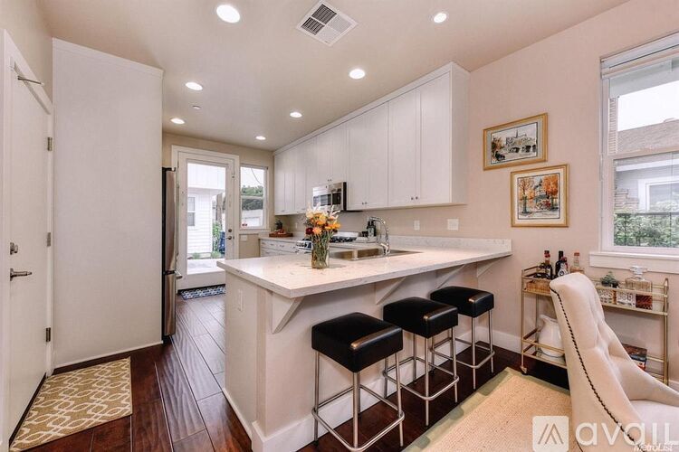 A kitchen with white cabinets and a bar area with stools.