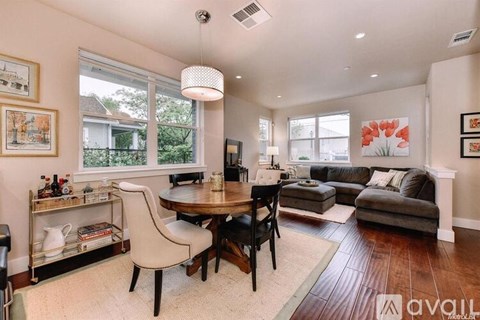 A well-lit living room with a dining table and chairs.