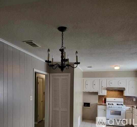 A kitchen with white cabinets and a chandelier.