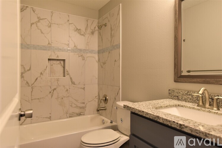 A bathroom with a marble tile wall and a white toilet.