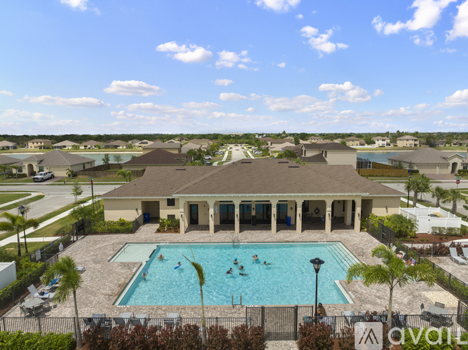 A large swimming pool in front of a house with people swimming.