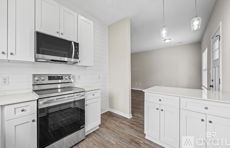 A kitchen with white cabinets and appliances.