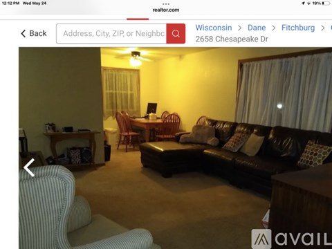A living room with a black couch and a striped armchair.