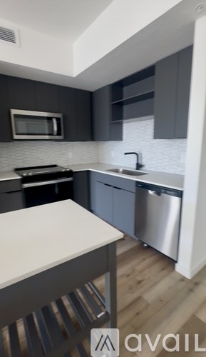 A kitchen with a white counter top and a stainless steel dishwasher.
