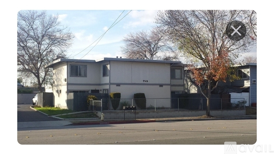 A house with a white facade and a tree with orange leaves in front.