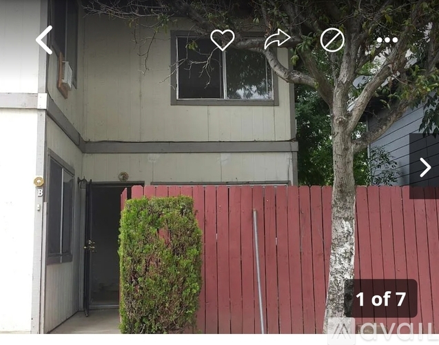 A house with a red fence and a tree in front.
