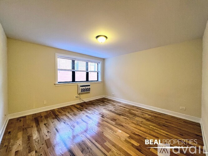 A room with wooden flooring and a window with blinds.