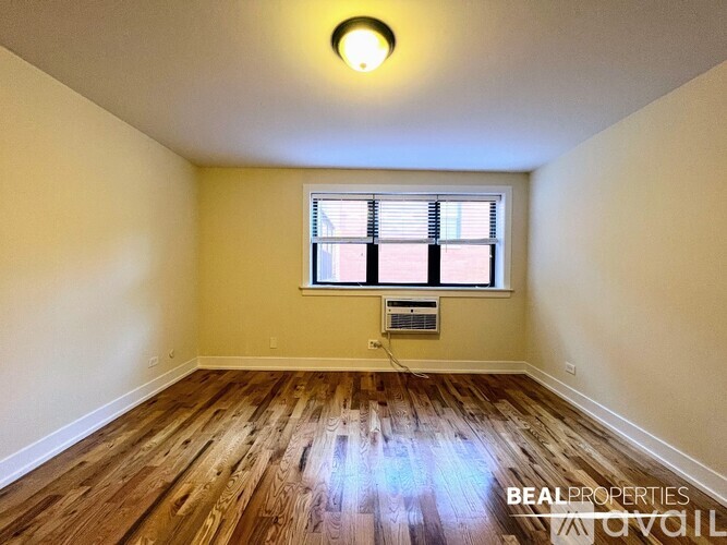 A room with wooden flooring and a window with blinds.