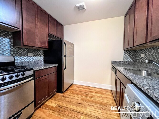 A kitchen with wooden cabinets and a black refrigerator.