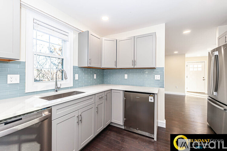 A kitchen with white cabinets and a blue tile backsplash.