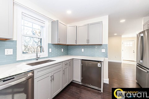 A kitchen with white cabinets and a blue tile backsplash.